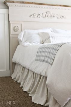 a bed with white linens and ruffled bedspread