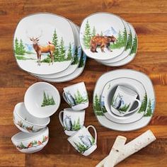 an assortment of dishes and cups with moose designs on them sitting on a wooden floor