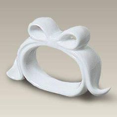 a white ceramic ring with a bow on the front and center piece in the middle