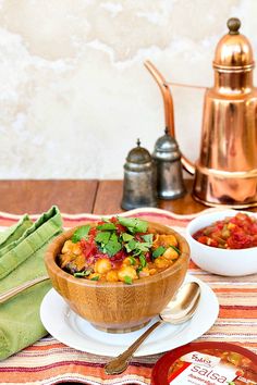 a wooden bowl filled with food on top of a table next to a cup and saucer