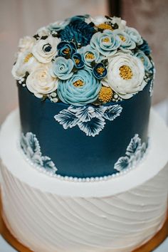 a blue and white wedding cake with flowers on top