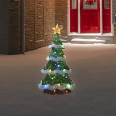 a lighted christmas tree in front of a red door