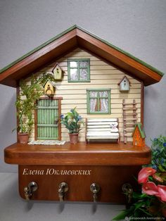 a doll house is sitting on top of a shelf with flowers and plants in front of it