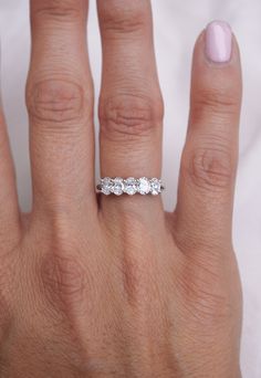 a woman's hand with a three stone ring on her left hand and a pink manicured nail