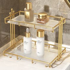 a gold bathroom shelf with two bottles and soaps on the bottom, in front of a marble wall