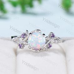 a white opal ring with purple stones on it