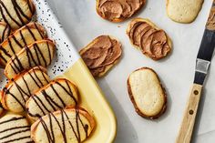 cookies with chocolate drizzled on them next to a cutting board and knife