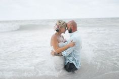 a bride and groom kissing in the ocean