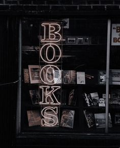 a book store window with books on display in the front and neon sign above it