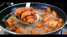 fried food being cooked in a pan on the stove with a ladle full of oil