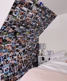 a bed sitting under a slanted ceiling next to a wall covered in pictures