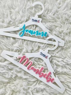 two personalized wooden clothes hangers on a white furnishing with pink and blue lettering