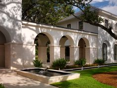 a large white building with arches and water feature in the front yard area on a sunny day