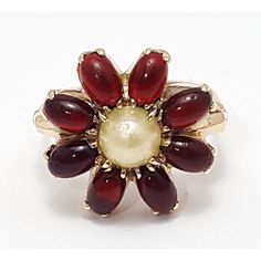 a red and white flower shaped ring with pearls on it's center, sitting on a white surface