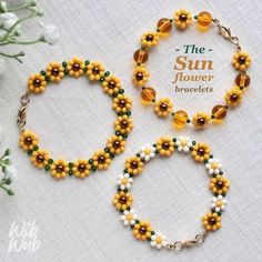 three bracelets with yellow and green beads on white table cloth next to flower bouquet