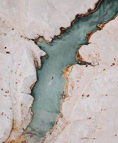 an aerial view of a person in a kayak on a river surrounded by mountains