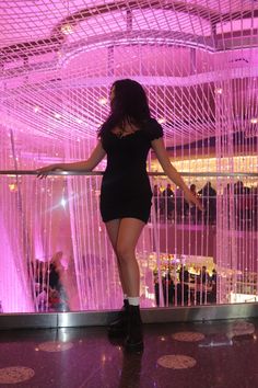 a woman is standing in front of a pink curtain and looking down at the floor