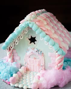 a pink, blue and white cake with a house on it's side sitting on a table