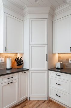 a kitchen with white cabinets and black counter tops, along with wood flooring in the middle