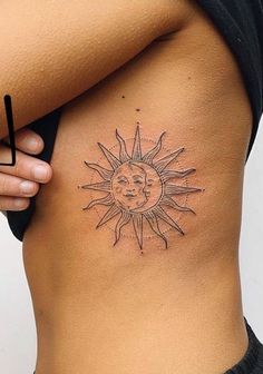 a woman's stomach with a sun tattoo on it