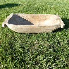 a wooden bowl sitting in the grass on top of it's side, with one end missing