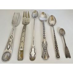 an assortment of silverware including spoons, forks and spoons with designs on them