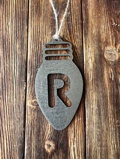 a metal ornament with the letter r hanging on a wooden wall next to a string