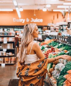 a woman standing in front of a produce section at a grocery store with her back to the camera