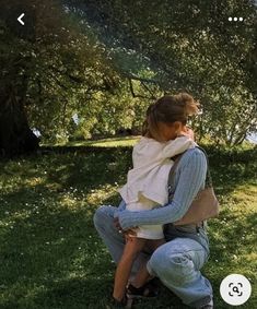 a man and woman sitting on the ground in front of trees with their backs to each other