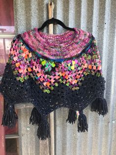 a colorful crocheted shawl hanging on a wall