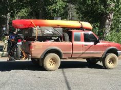 a red pick up truck with a kayak strapped to the back