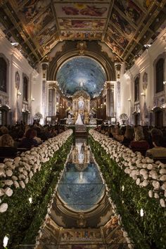 the inside of a church with flowers and greenery on the floor, reflecting in the water