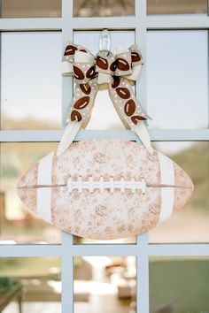 a football hanging from the side of a window with a bow on it's head