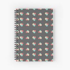 a spiral notebook with pastel circles on a dark grey background that has pink, blue, and green polka dots