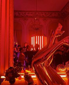 a group of people standing around in a room with red lights on the walls and floor