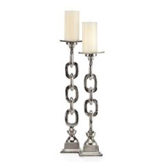 two metal candles with chains attached to each other on a white background, one candle is lit and the other is turned off