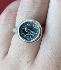 a close up of a person's hand wearing a ring with a coin on it