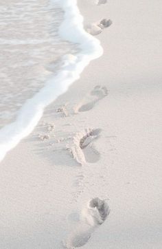 two footprints in the sand next to an ocean