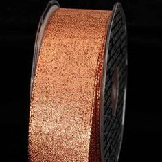 a roll of metallic ribbon with black and orange glitter on the side, against a black background