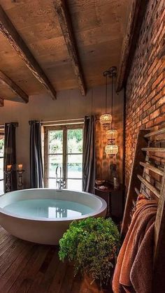 a bathroom with a large bathtub next to a brick wall and wooden flooring