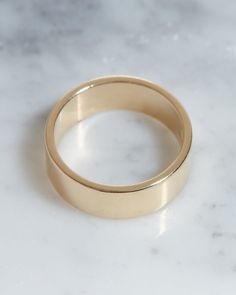 two gold wedding bands sitting on top of a white marble countertop next to each other