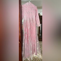 a pink dress is hanging on a door frame in front of a doorway with an ornate carpeted floor