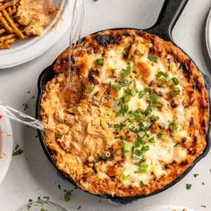 a skillet with some food in it and plates on the table next to it