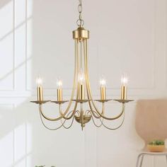 a gold chandelier with five candles hanging from the bottom and one light on top