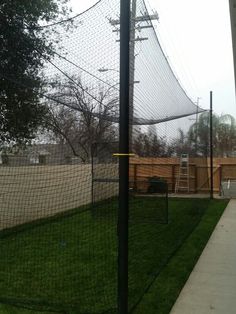 a baseball field with a fence and green grass on the side walk next to it