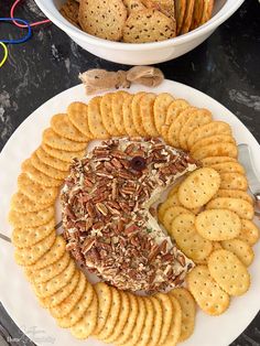 a plate with crackers and cheese on it next to a bowl of crackers