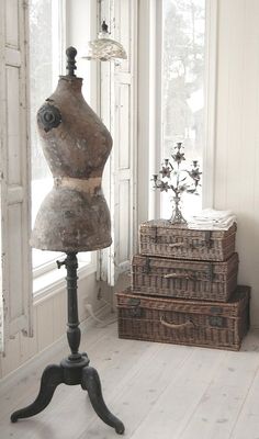 an old fashion mannequin sitting on top of a table next to some trunks