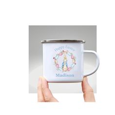 a person holding a white coffee mug with the words happy easter and an image of a rabbit on it