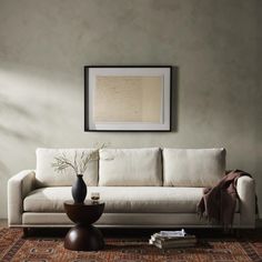 a living room with a couch, table and vase on the floor in front of it