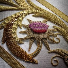 an embroidered piece with gold and pink flowers on it